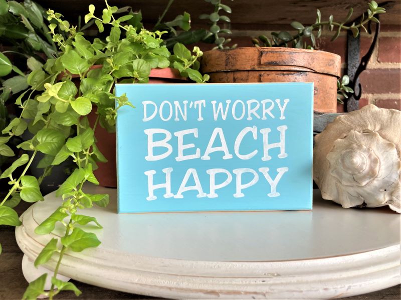 4x6 inch wood sign.  Aqua with white lettering saying Don't Worry Beach Happy.