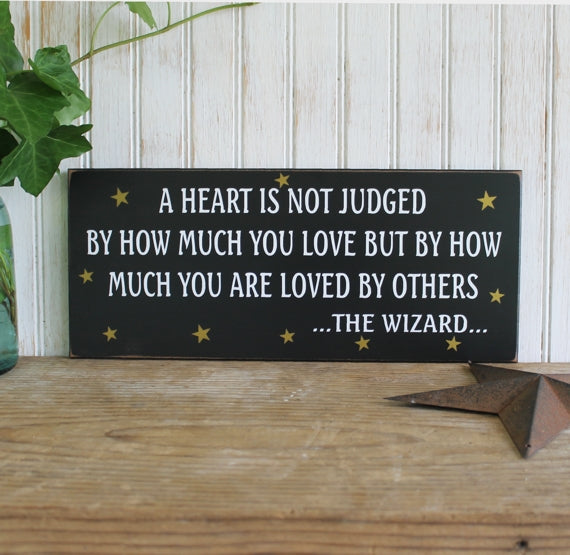 A heart is not judged wood sign 6x14 inches. Black worn finish with white letters and gold stars.  Tin man quote. Wizard of Oz.