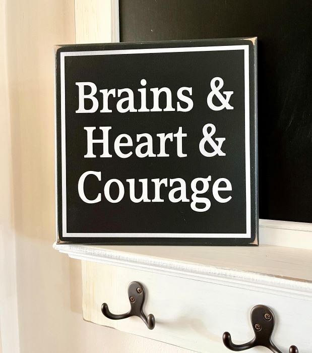 Wizard of Oz Wood Sign. Blaclk worn finish background with white wording that says, Brains & Heart & Courage. Available in two sizes.