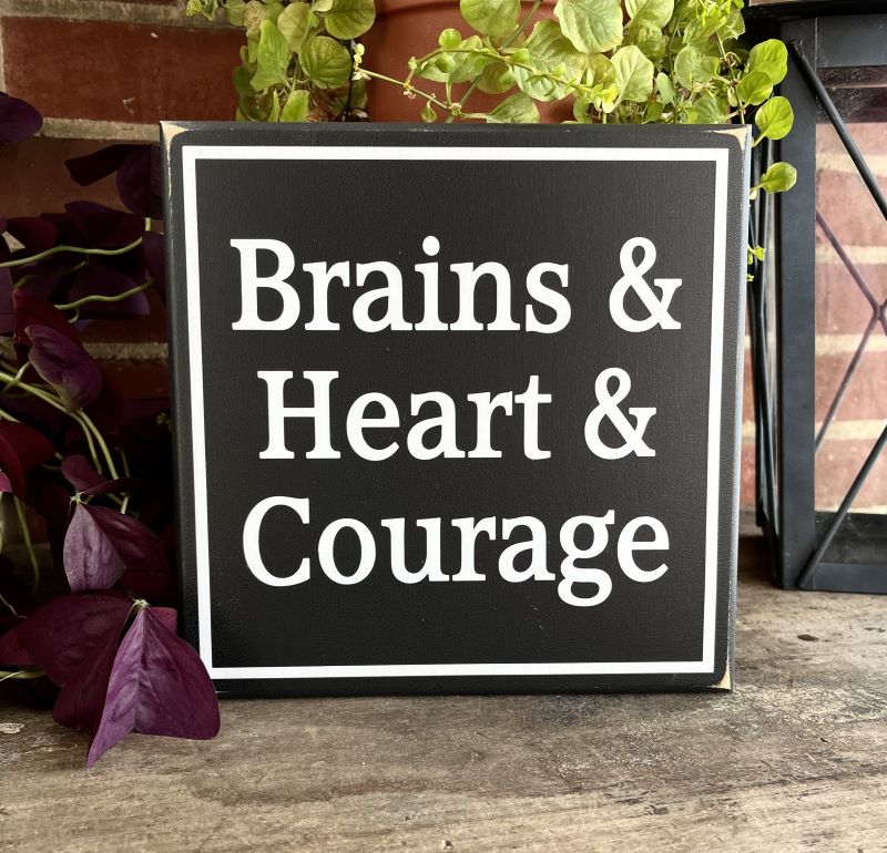Wizard of Oz Wood Sign. Blaclk worn finish background with white wording that says, Brains & Heart & Courage. Available in two sizes. 