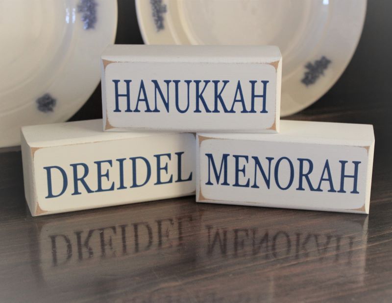 Hanukkah Dreidel Menorah Stacking Blocks Sweet set of 3 wooden stacking Holiday blocks. Each block measure 1.75x4inches White with blue lettering Display on a tiered tray. Tuck on a shelf or sit on a mantel.
