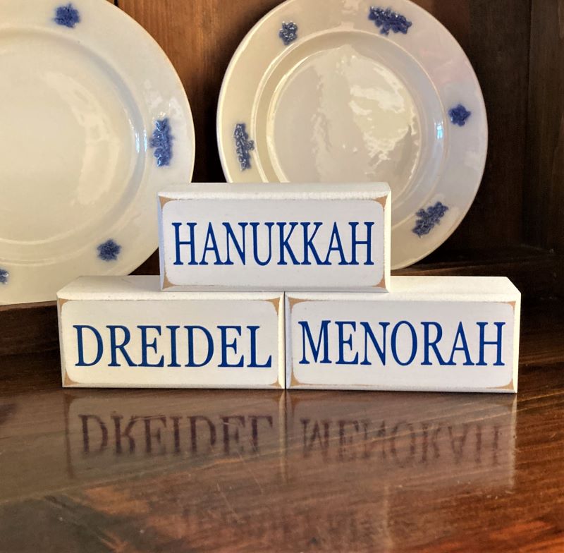 Hanukkah Dreidel Menorah Stacking Blocks Sweet set of 3 wooden stacking Holiday blocks. Each block measure 1.75x4inches  White with blue lettering Display on a tiered tray.  Tuck on a shelf or sit on a mantel. 