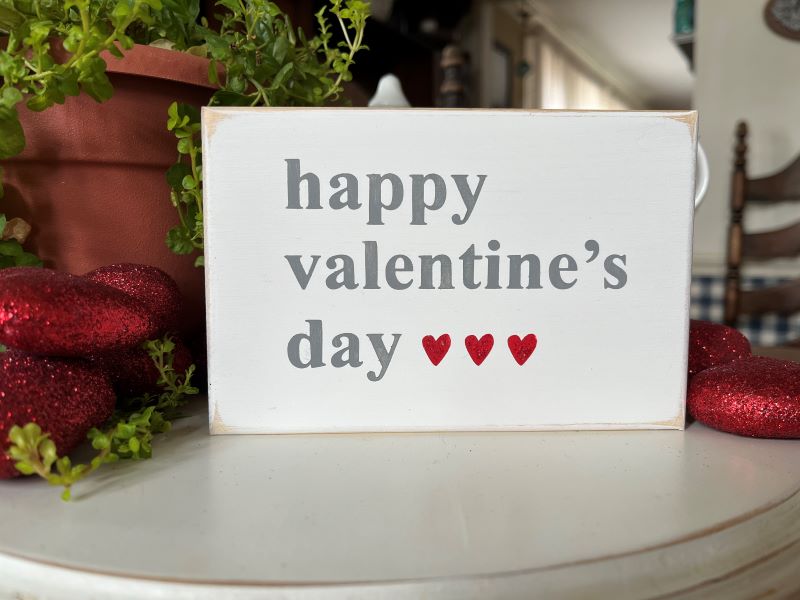Happy Valentine's Day Wood Sign. Worn white with gray letters and 3 small red glittered hearts. Sign measures 4x6 inches. Hand painted tiered tray decor.
