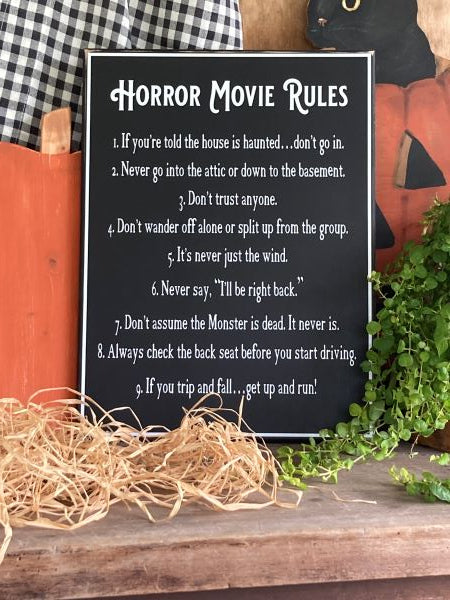 12x16 inch black worn finish sign. White lettering and border. Horror Movie Rules. A list of 9 rules to follow if you are watching or in a horror or spooky movie.