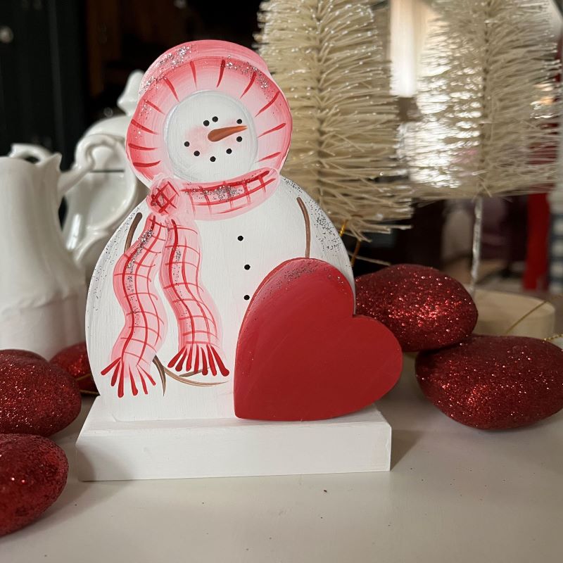 Hand painted Valentine Snowman sitting on a wooden base. Pink and red hat and scarf and a red heart sitting in front with a bit of glitter to add some sparkle. 5 inches tall and 4 inches wide.