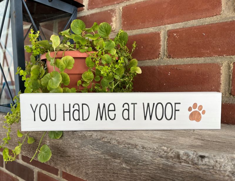 White wood sign with hand stenciled words saying, You had me at woof with a paw print. 2 1/2 inches x 12 inches #doglife #dogmom 