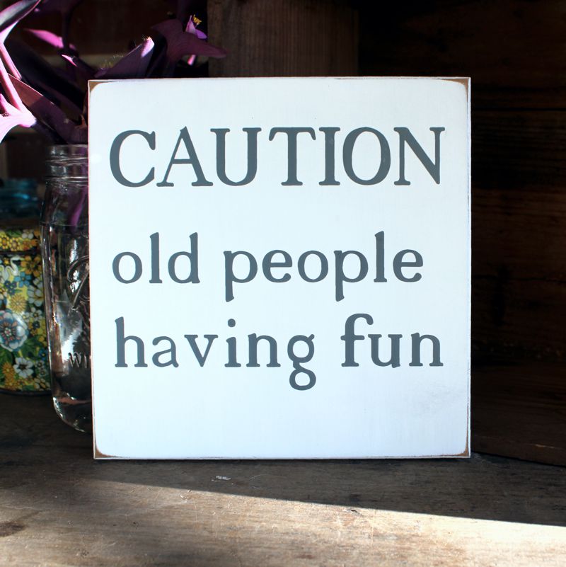 The wording Caution. Old people having fun in gray lettering on a white worn finish wood sign.  Sign  measures 8x8 inches.  Other size and colors available.