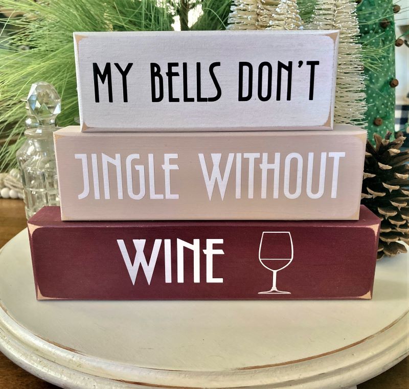Set of 3 blocks. Top block white with black letters saying MY Bells Don't. Middle block tan with white letters saying Jingle Without. Bottom block burgundy with white lettering saying Wine and a graphic of a wine glass. 6 3/4 h x 9 w x 1 1/2 inches.